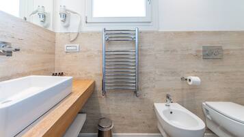 Un baño moderno con una bañera grande, un bidé y un perchero para toallas.