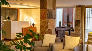 Un salon chaleureux avec un canapé, des fauteuils, une table basse avec des livres, une cheminée et un mur d’accent en pierre.