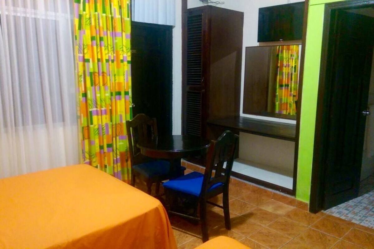 Um quarto com uma mesa de jantar, duas cadeiras, uma mesinha e um armário.