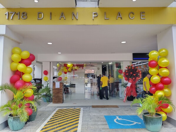 The entrance of a hotel named "1718 Dian Place" with yellow and red balloons, potted plants, and a blue handicap accessibility sign.