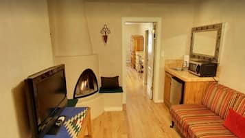Una sala de estar acogedora con televisión, chimenea, sofá y zona de cocina.