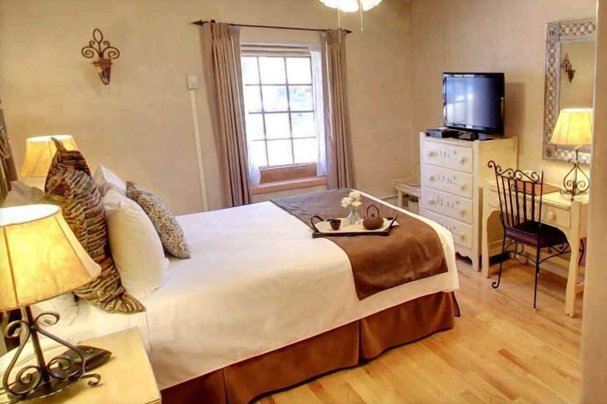Una camera da letto con un letto, una televisione, una scrivania e una sedia.