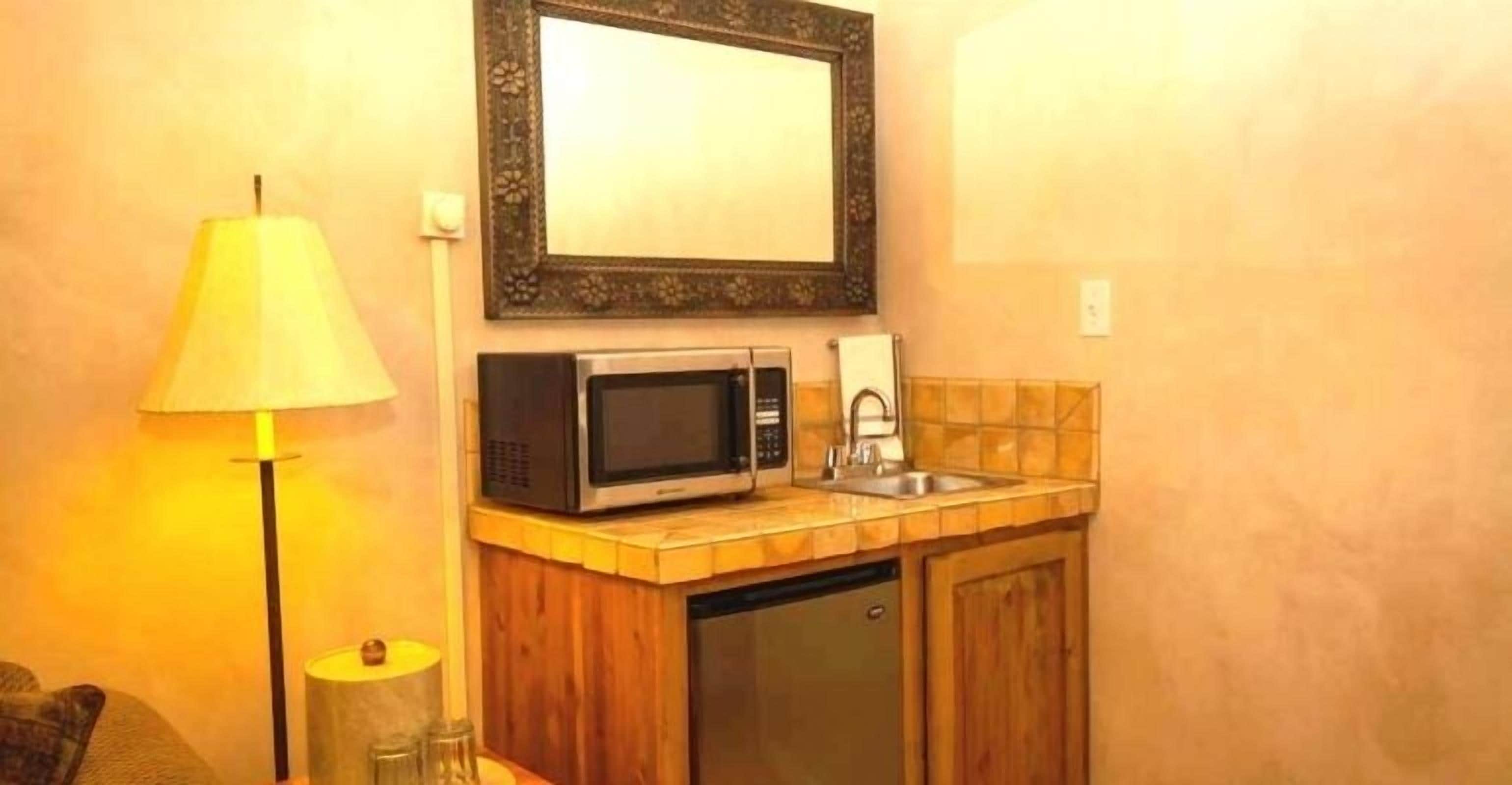Una kitchenette compacta con microondas, pileta y alacena.