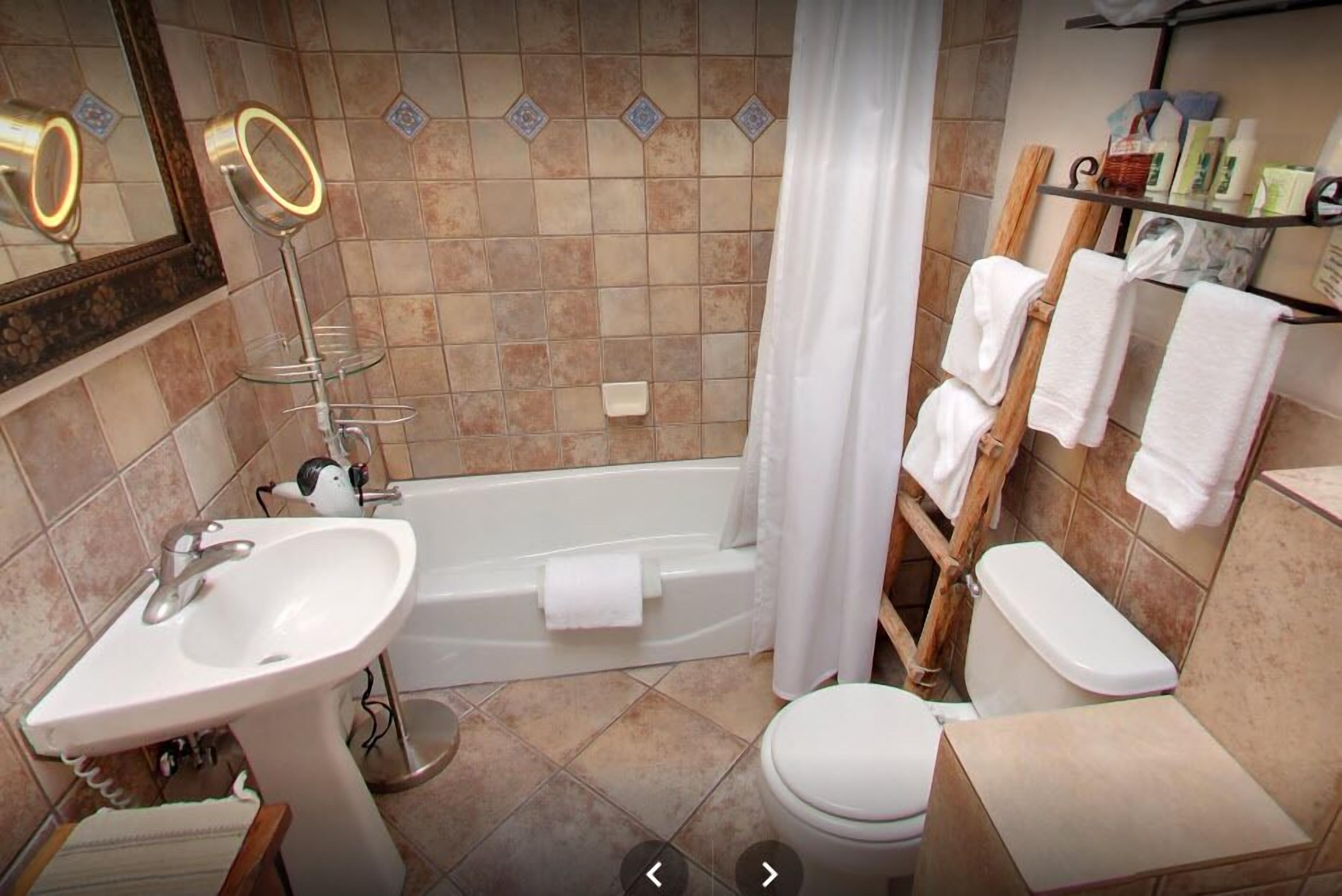 A bathroom with a sink, mirror, bathtub, toilet, and towel rack.