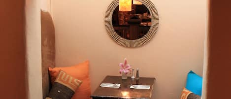 A cozy seating area with a cushioned bench, a small table with a mirror, and a wall-mounted shelf.