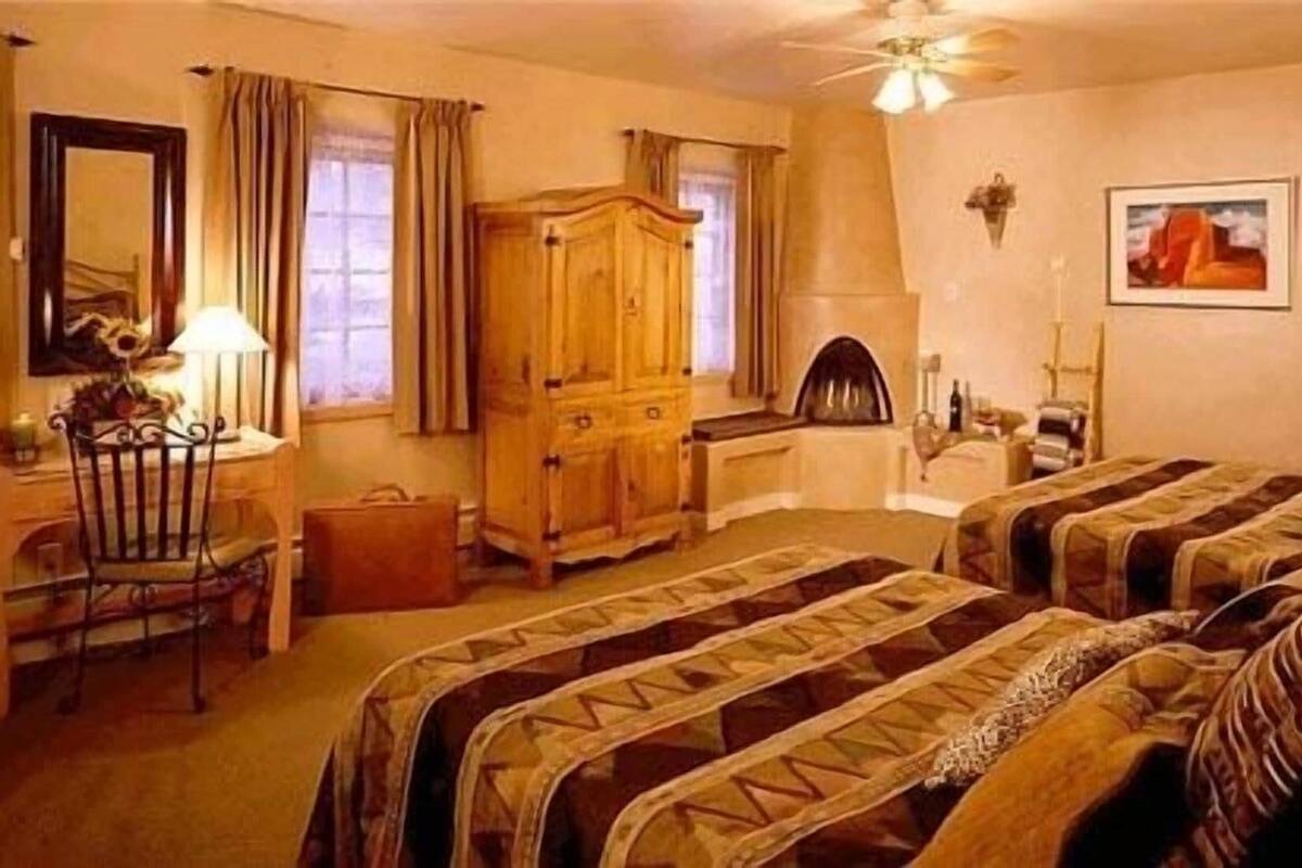 Una stanza con due letti, un armadio in legno, una scrivania con una sedia, una lampada e un quadro appeso al muro.