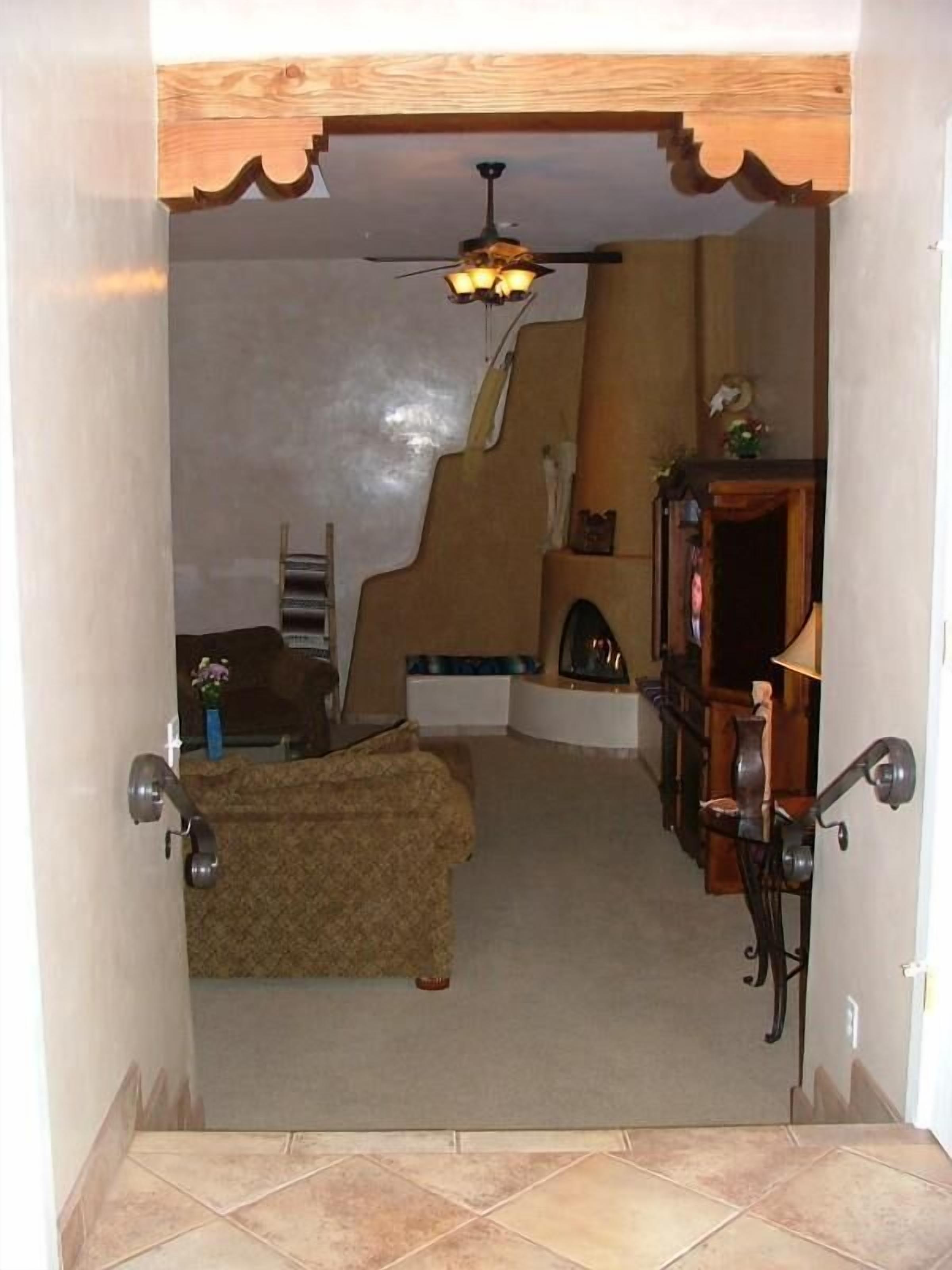 A narrow hallway with a ceiling fan, a wooden bench, and a small table with a lamp.