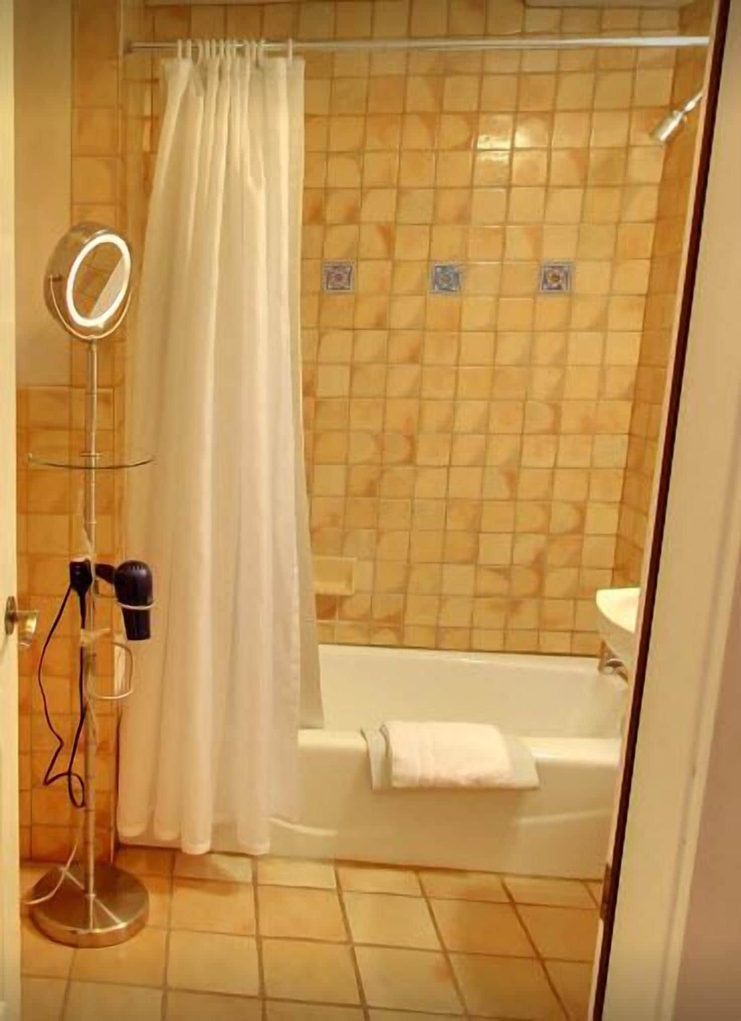 A bathroom with a shower, a bathtub, a mirror, and a hairdryer.