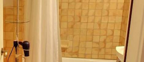 A bathroom with a shower, a bathtub, a mirror, and a hairdryer.