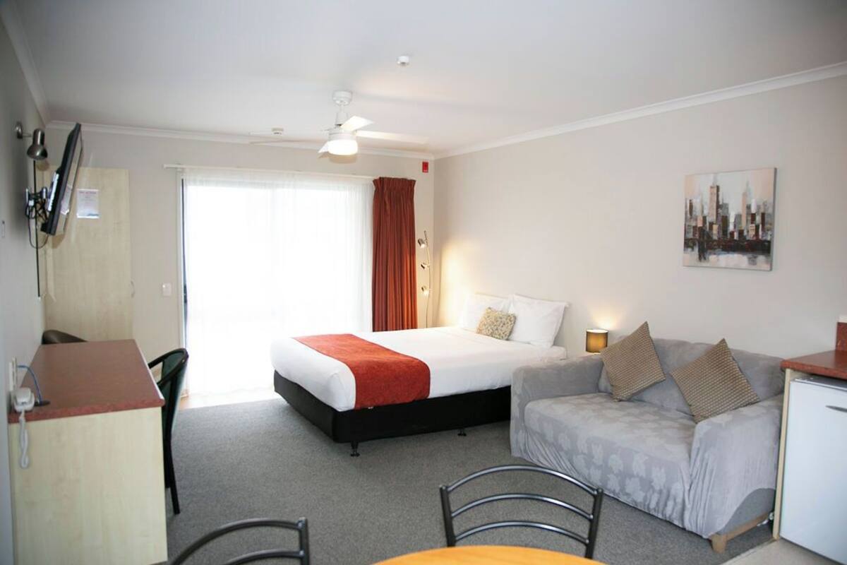 A hotel room with a bed, a sofa, a desk, and a chair.