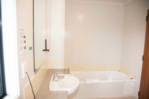 Un baño con lavamanos, espejo y bañera.