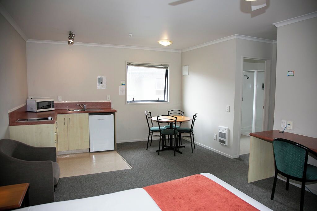 Una habitación compacta con kitchenette, zona de comedor y cama.