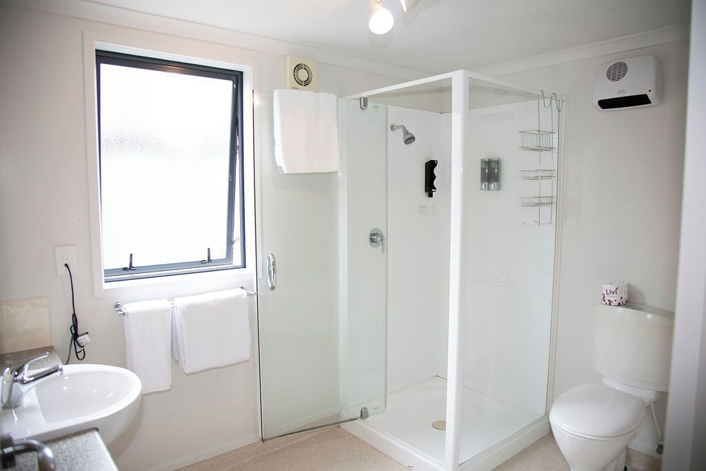Un baño moderno con ducha de vidrio, un lavabo blanco y un inodoro.