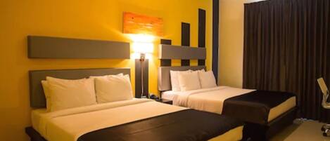 A hotel room with two beds, a desk, a lamp, and a large window with curtains.
