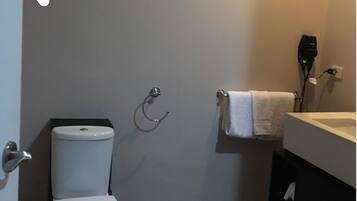 A small bathroom with a toilet, a towel rack, and a sink with a mirror.