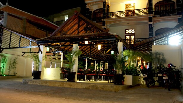A multi-story building with a covered outdoor seating area, potted plants, and a staircase leading to an upper level. - Thyda Villa (Siem Reap)