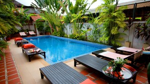 A pool area with lounge chairs and tables, surrounded by potted plants and a tiled floor. - Thyda Villa (Siem Reap)