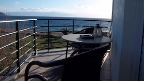 Un balcón con mesa y sillas con vistas al océano.