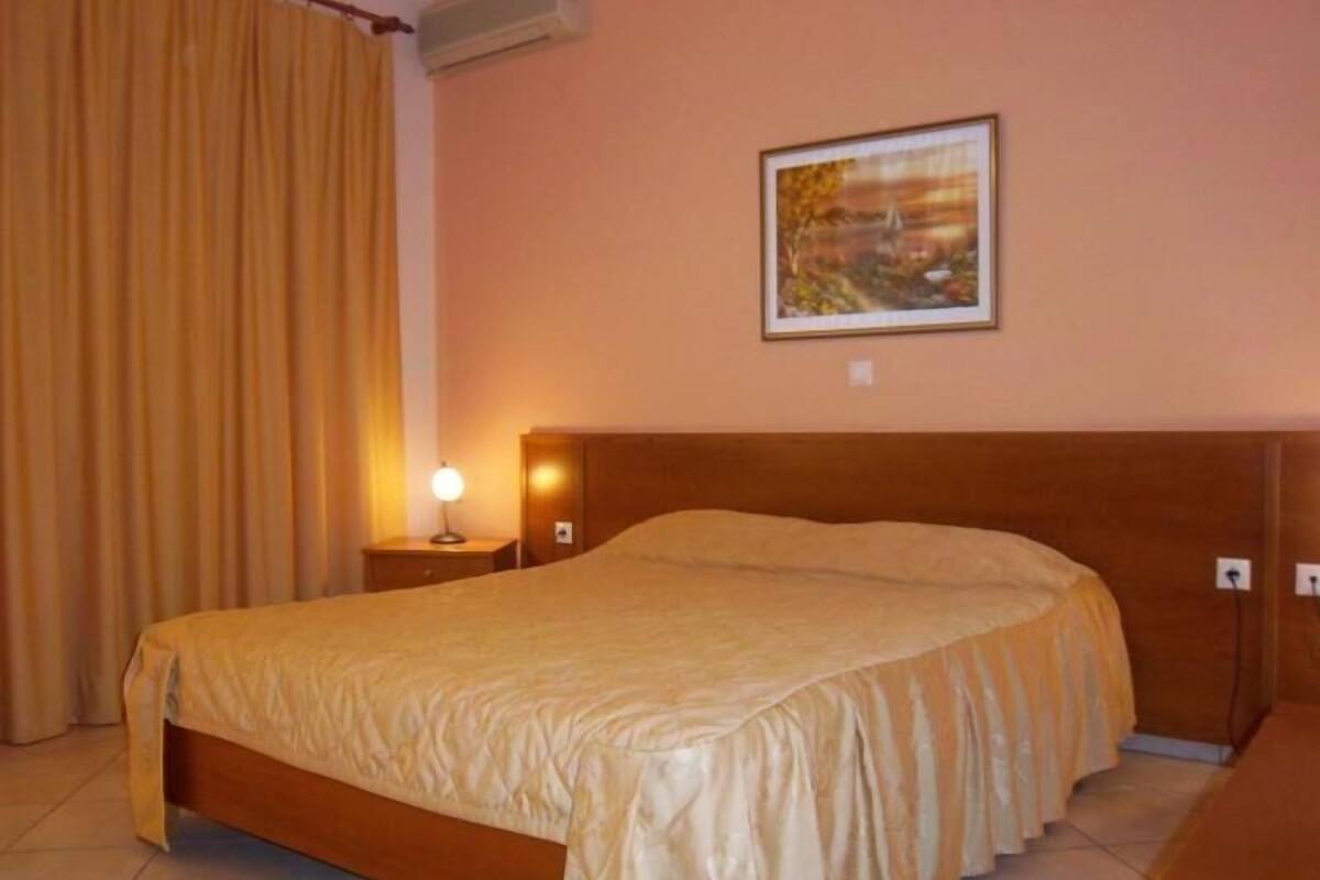 Une chambre à coucher avec un lit, une table de chevet, une lampe, un tableau au mur et une fenêtre avec des rideaux.