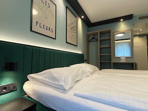 Relax in a stylish room with a comfortable bed, a wall-mounted shelf, and artwork featuring floral designs.