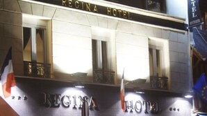 Het uiterlijk van Hotel Regina, met een bord, grote ramen en vlaggen.