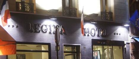 Exterior del Hotel Regina, con un cartel, ventanas amplias y banderas.