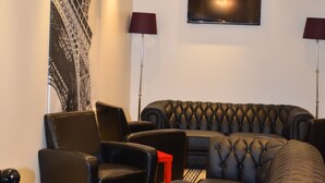 Een moderne woonkamer met een grote hoekbank, twee fauteuils, een flatscreen televisie en een wandairconditioner.