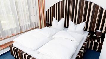 A double bed with white linens, a striped headboard, and a bedside table with a lamp.