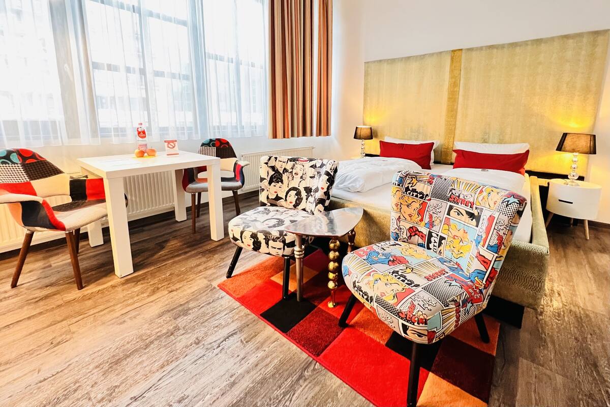 A hotel room with a bed, a desk, a chair, and a window with curtains.