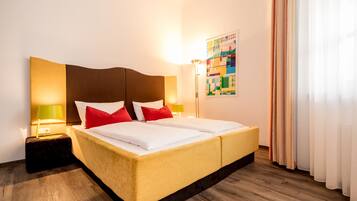 Een hotelkamer met een groot bed, twee bedlampen, een hoofdbord en een kleurrijk abstract schilderij aan de muur.