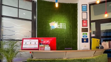Ein Empfangsschalter mit einem grünen Kunstgras-Hintergrund, einem gerahmten Willkommensschild und einer roten Theke.