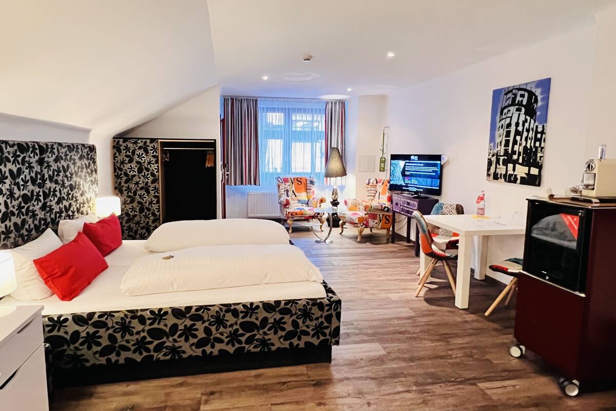 A hotel room with a bed, a desk, a TV, and a chair.