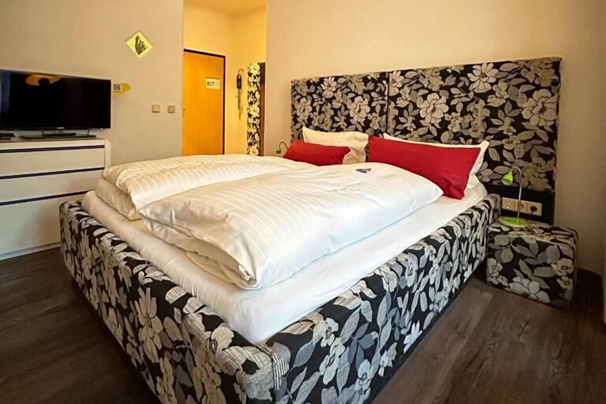 A modern bedroom with a large bed, a TV, and a floral headboard.