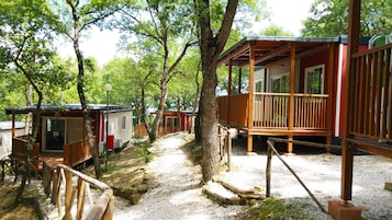 Un camping con cabañas de madera, senderos de grava y árboles.