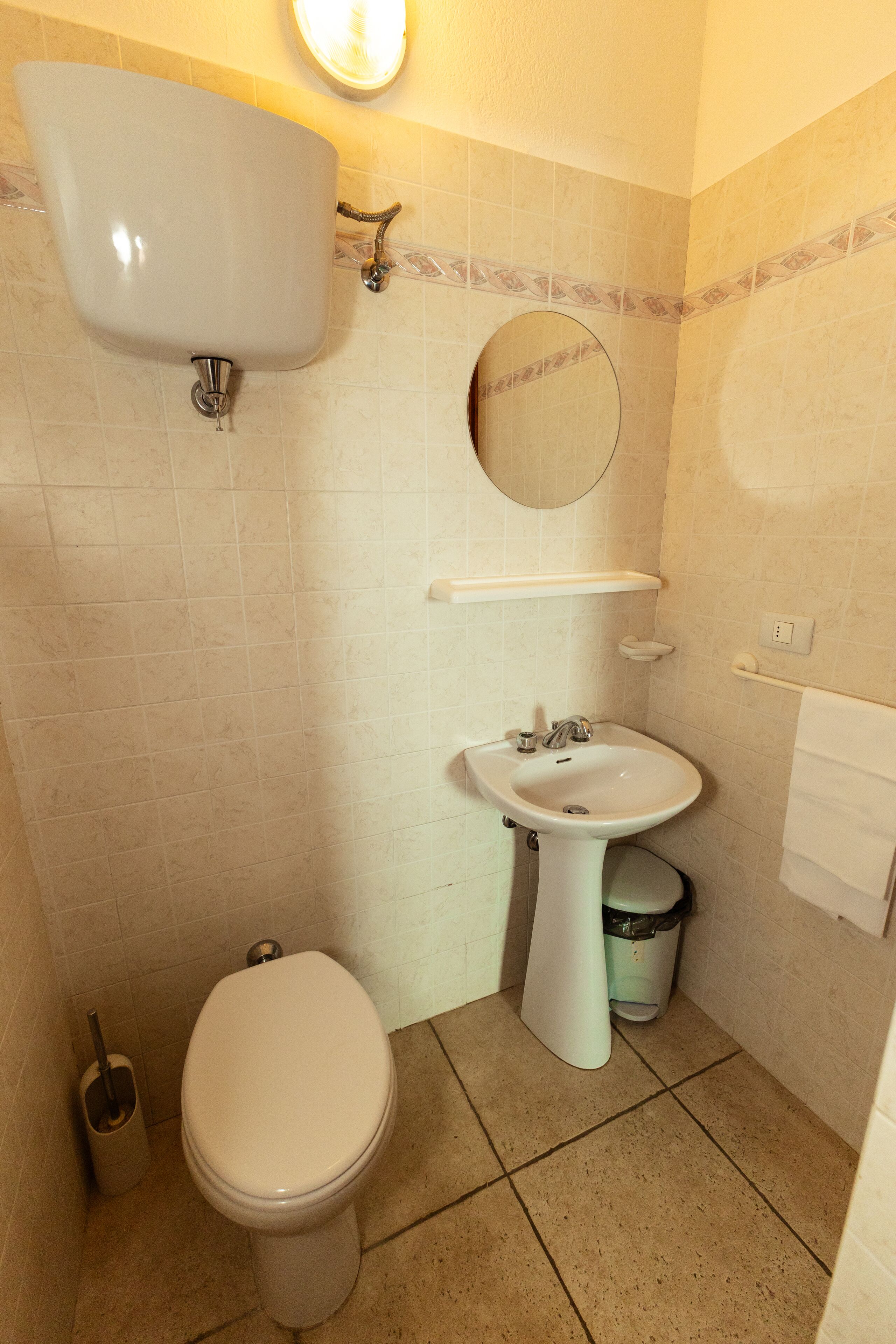 Un baño con inodoro, lavamanos y espejo.