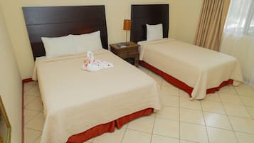 A hotel room with two beds, each with a headboard, a nightstand, and a lamp.