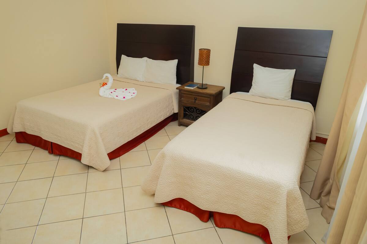 Two single beds with headboards, a nightstand with a lamp, and a swan decoration on the left bed.