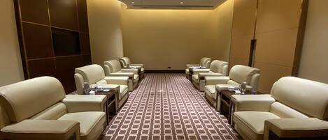 A hotel room with a long row of leather armchairs, a patterned carpet, and a recessed ceiling light.