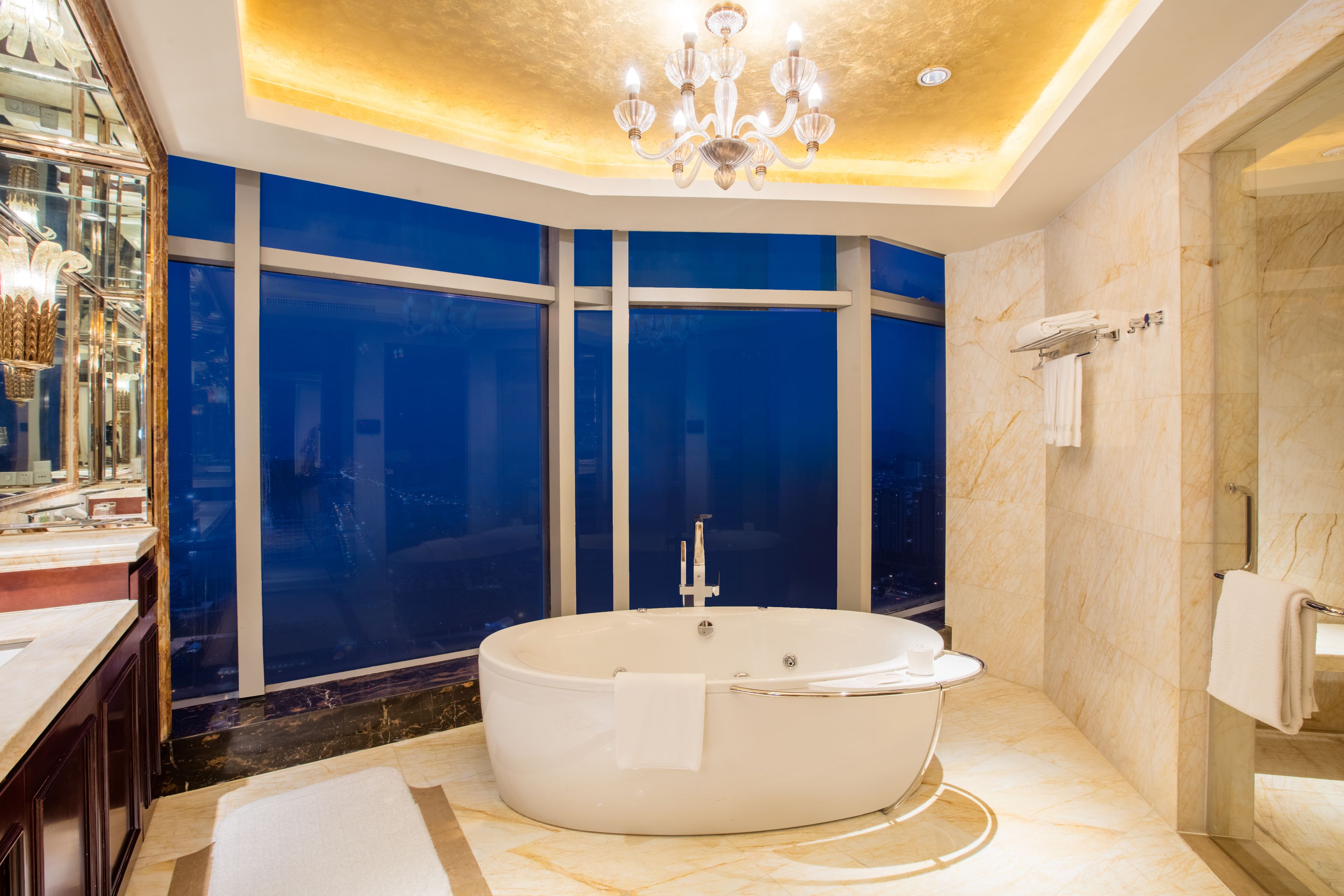 Un baño lujoso con una bañera independiente grande, una ducha con mampara de vidrio y un candelabro.