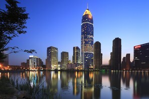 A city skyline with a prominent tower reflecting on a calm body of water. - Crowne Plaza Shaoxing by IHG (Shaoxing)