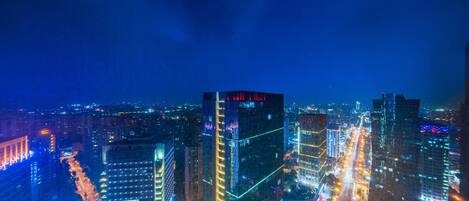 A nighttime cityscape with illuminated skyscrapers and busy streets.