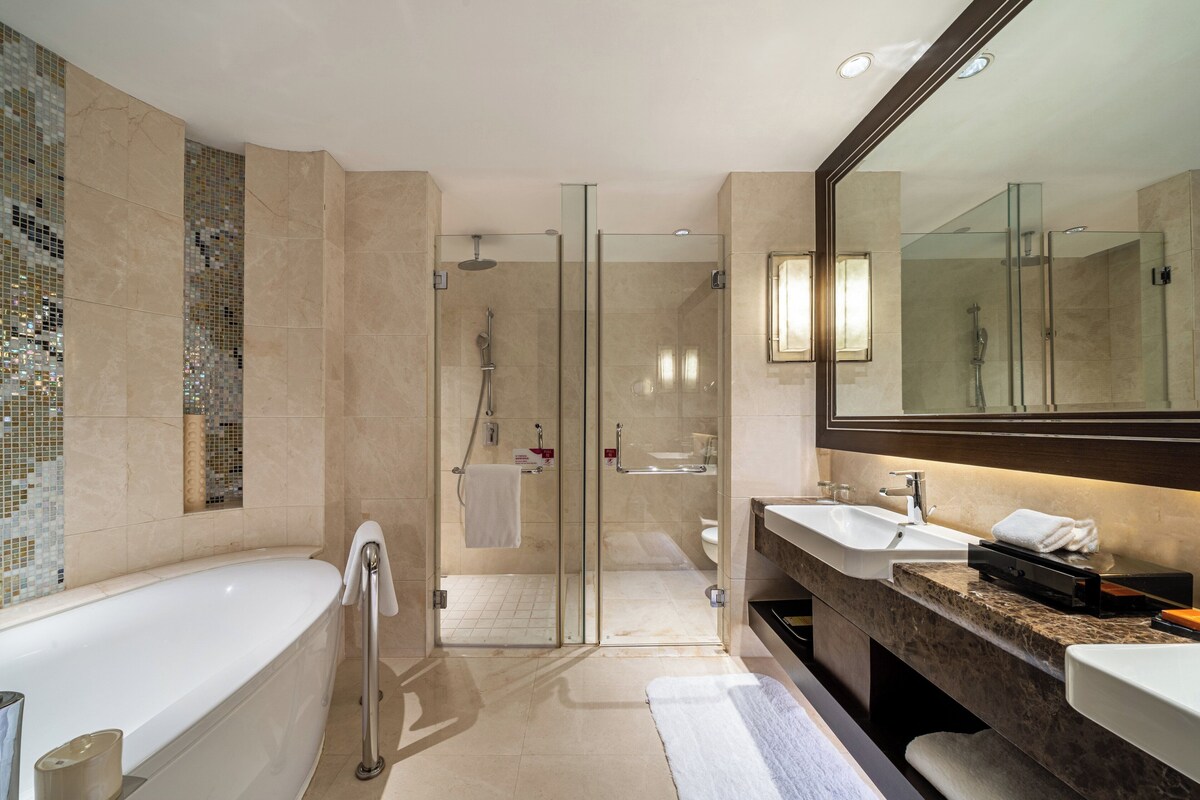 A modern bathroom with a glass-enclosed shower, a freestanding bathtub, and a vanity with a large mirror.