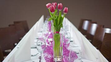 A table set with clear glassware, pink tulips, and a purple table runner.