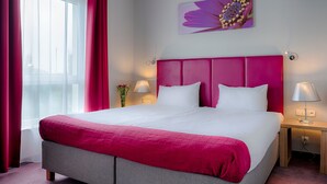 A hotel room with a large bed, a pink headboard, and a window with curtains. - Focus Hotel Katowice Chorzow (Chorzow)