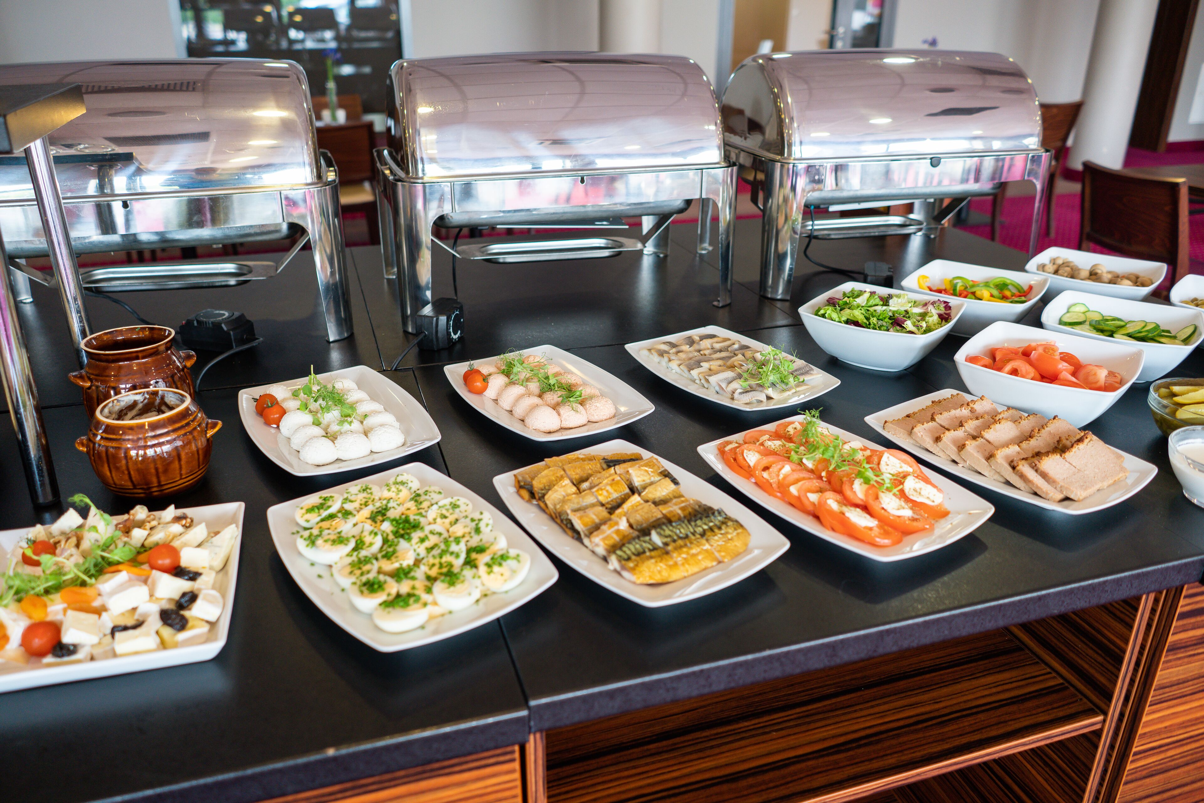 A buffet table with various food items and two barbecue grills.