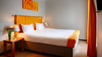 A hotel room with a large bed, two bedside tables, a wall-mounted TV, and a painting above the bed.