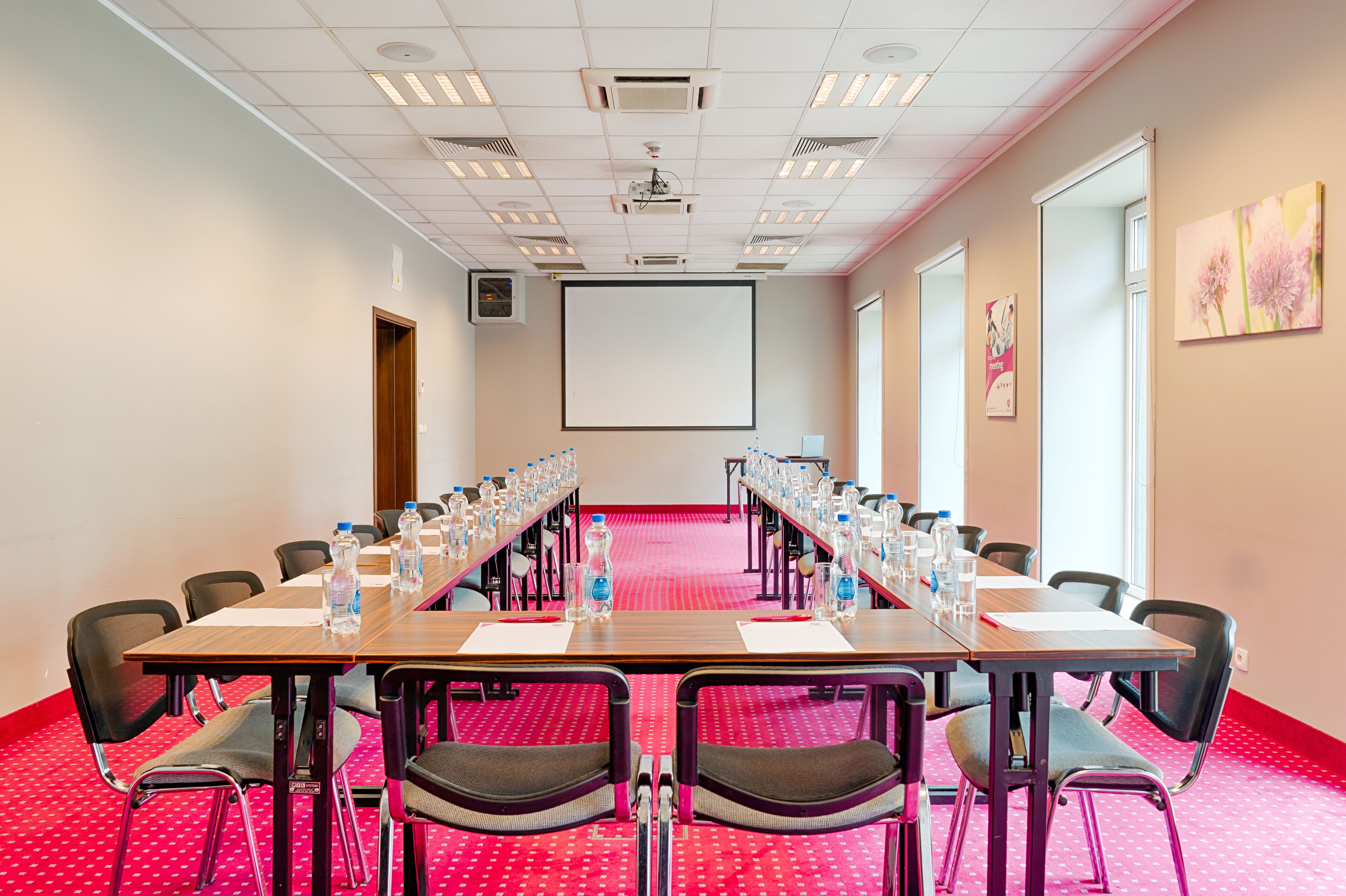 Une salle de conférence équipée d’une longue table, de chaises et d’un écran de projection.