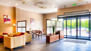 A hotel lobby with a reception desk, seating area, and large windows. - Focus Hotel Katowice Chorzow (Chorzow)