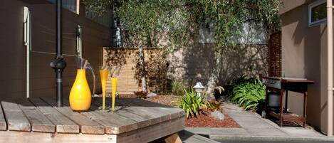 A wooden table with a large umbrella, two yellow vases, and a black lamp.