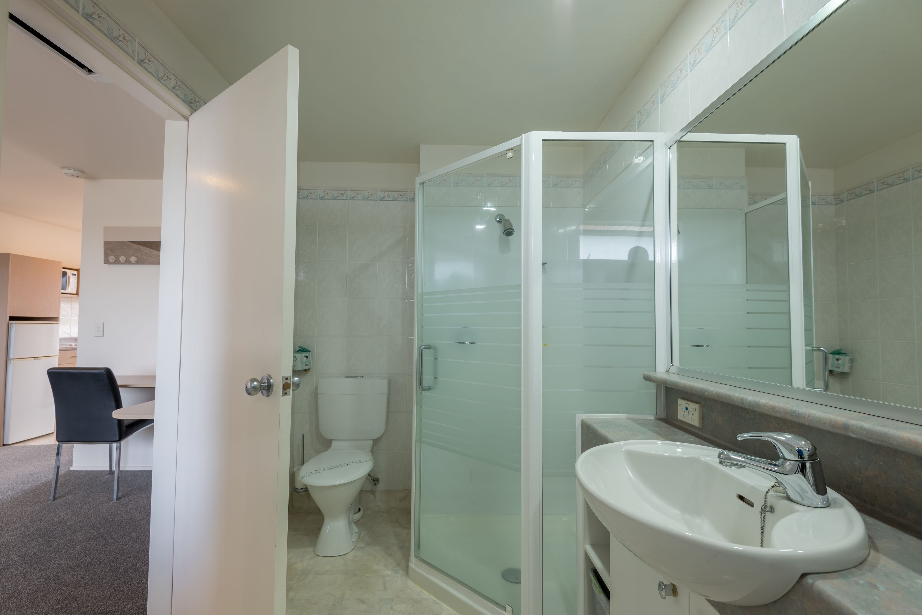 A bathroom with a glass-enclosed shower, a white sink, and a toilet.
